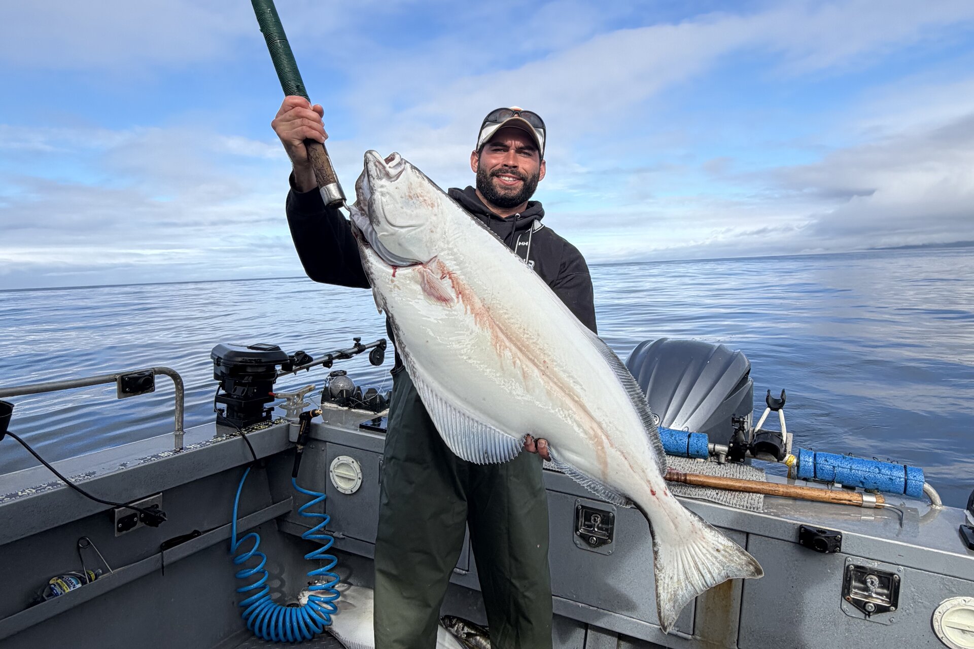 Angler holding a Pacific halibut aboard a boat off Port Renfrew, British Columbia