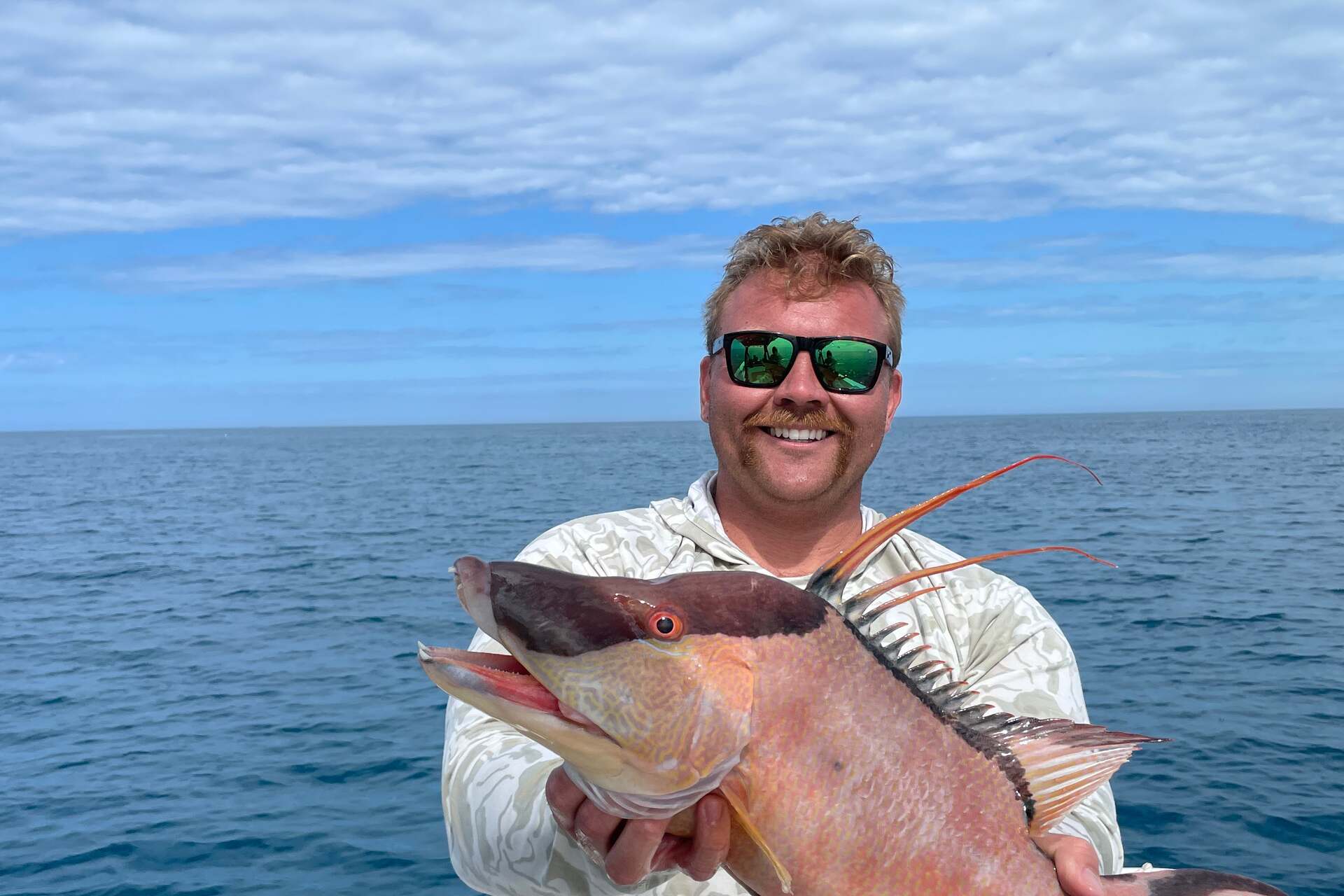 Angler holding a hogfish offshore, open Gulf water behind him