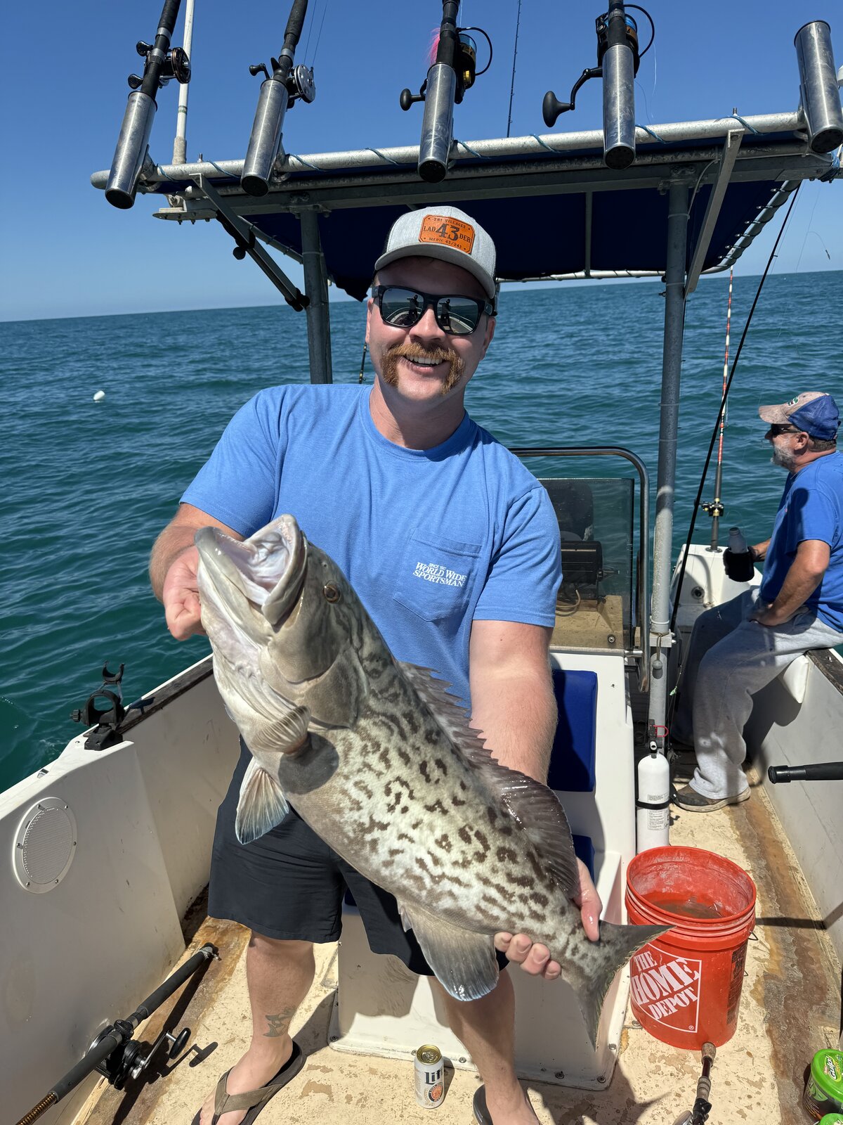 Angler aboard a boat holding a gag grouper with irregular dark markings